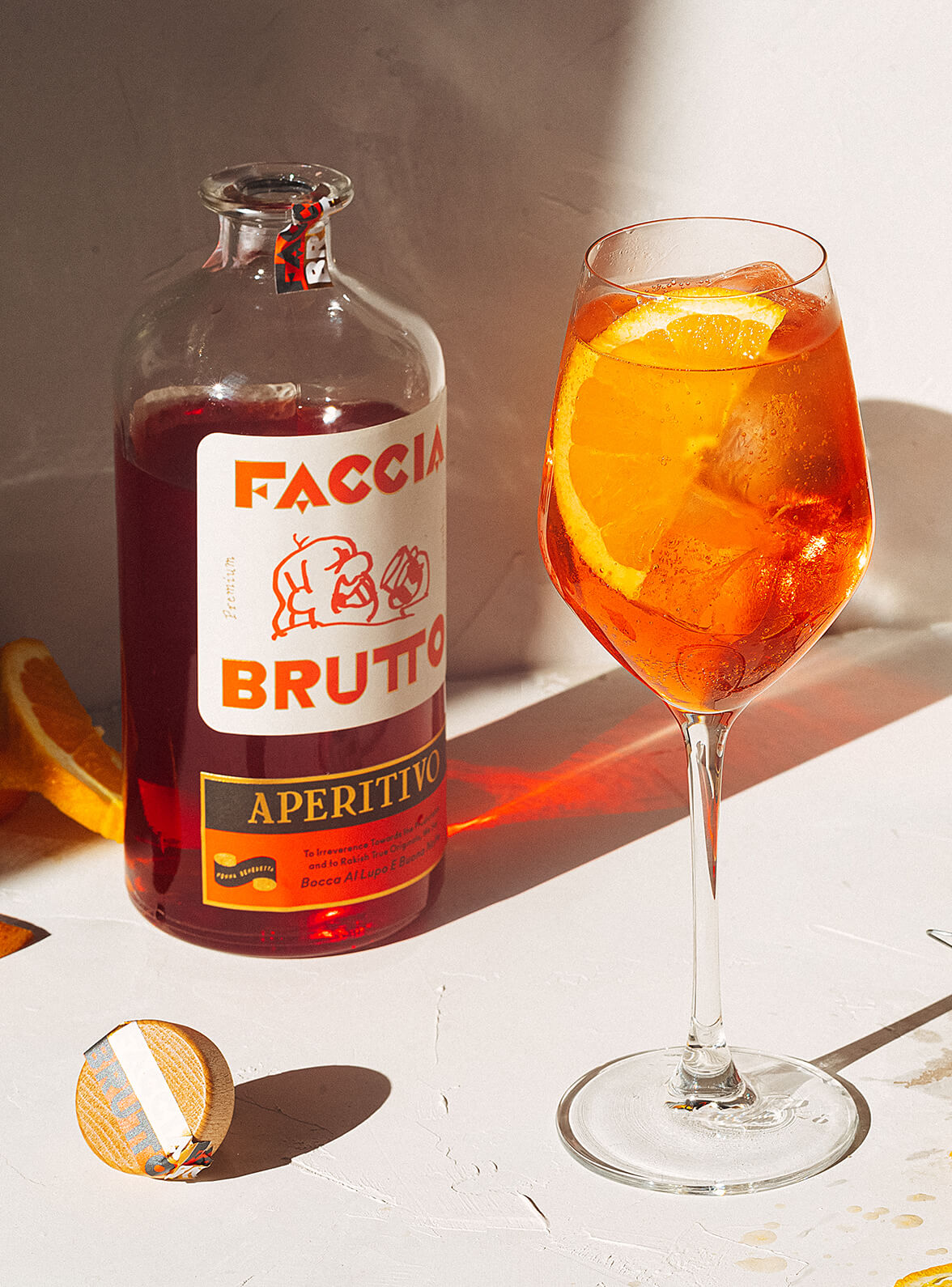 Open bottle of Faccia Brutto Aperitivo with aperitivo spritz in wine glass