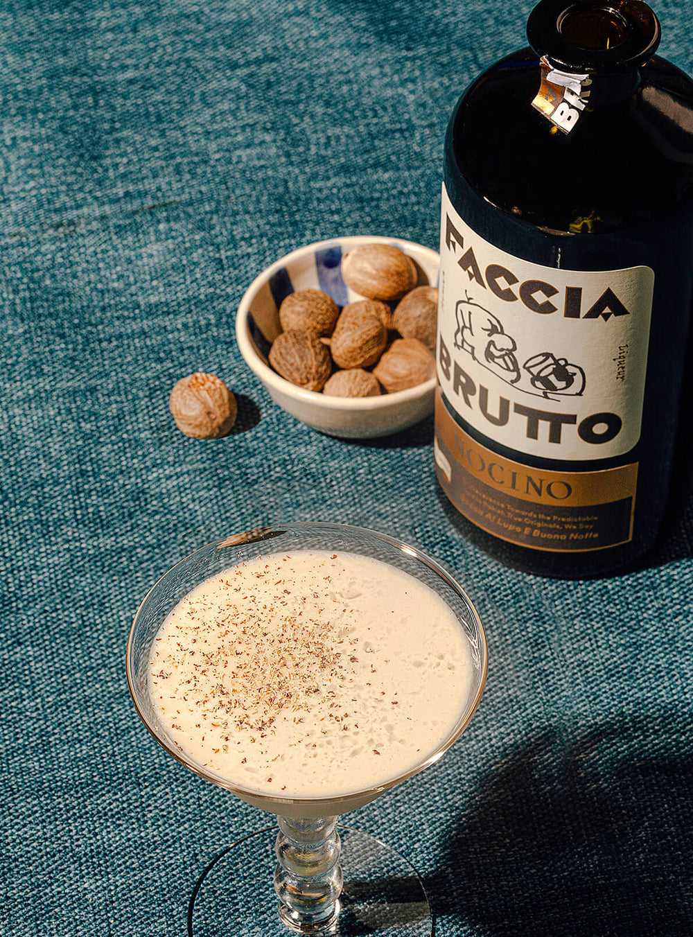 Creamy cocktail with fresh nutmeg and bottle of Faccia Brutto Nocino