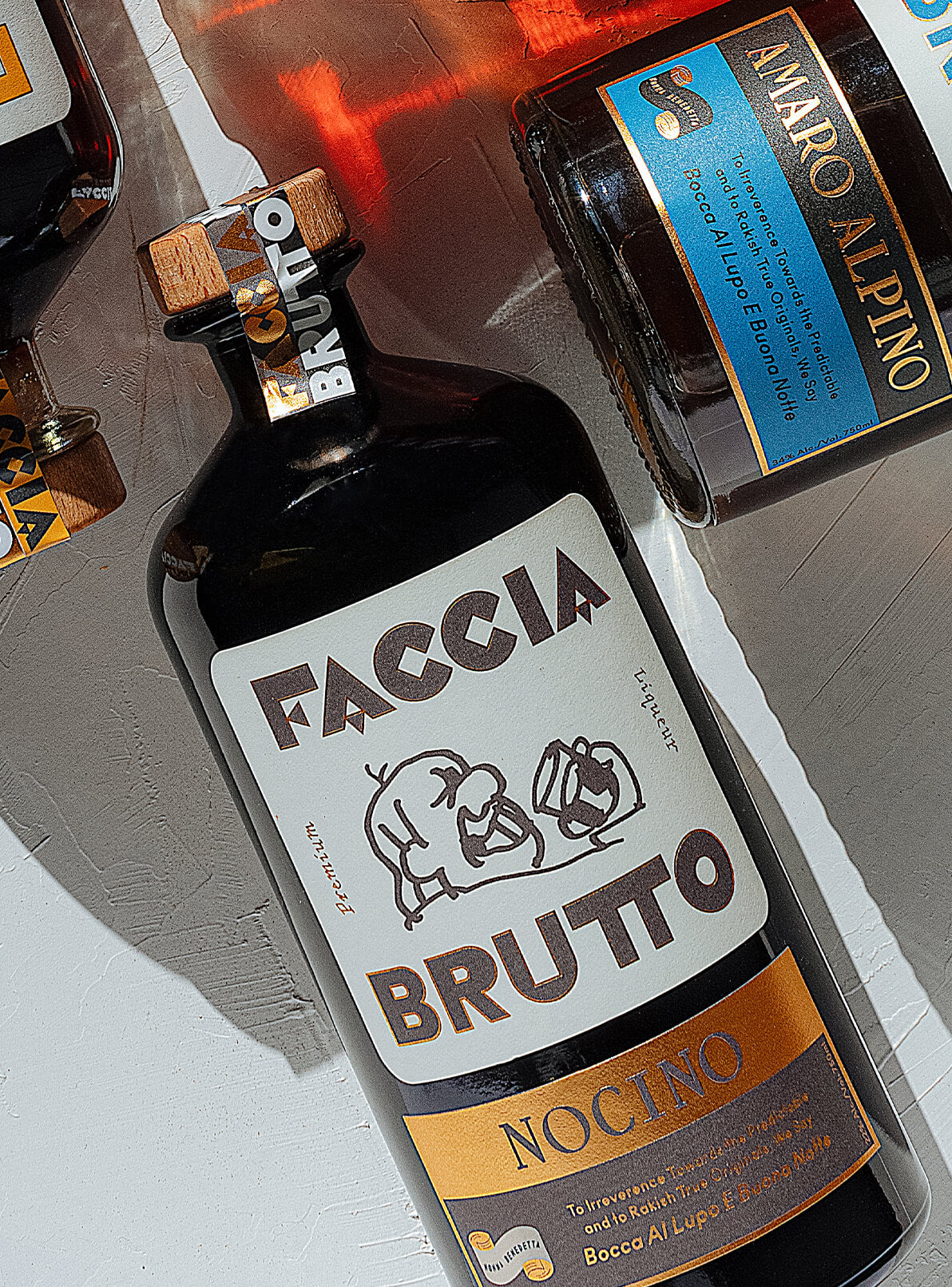 Faccia Brutto Nocino bottle laid down on white painted background