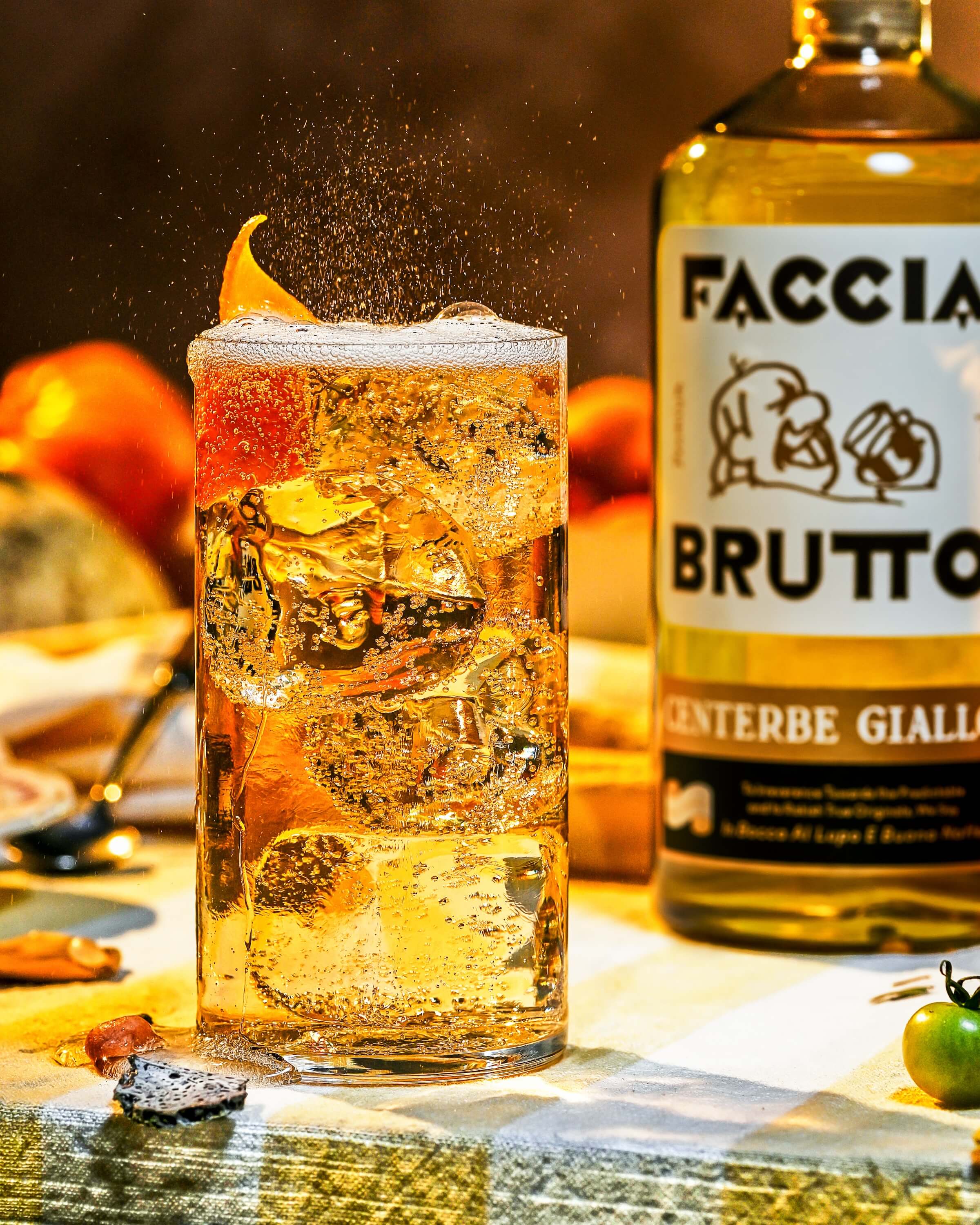 Glass with ice and fizz with Faccia Brutto Centerbe Giallo bottle in background