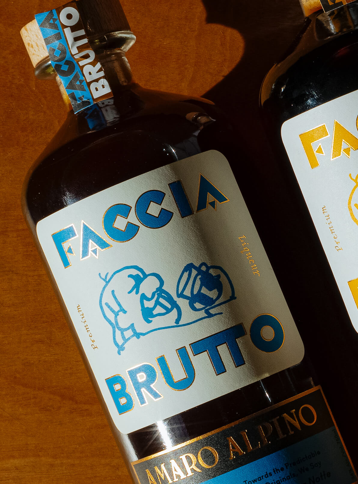 Bottle of Faccia Brutto Amaro Alpino laying down on wood background